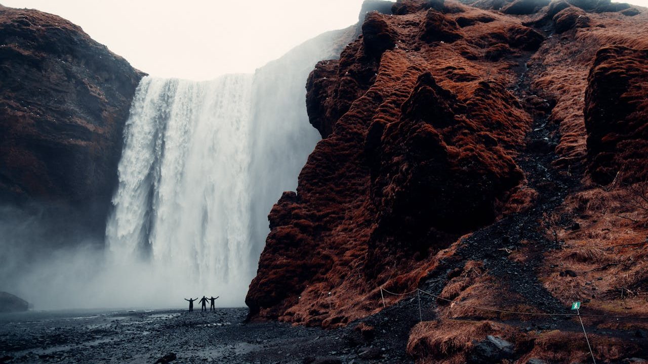 Three Men Standing Near Waterfalls